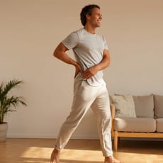 Menos dolor más movimiento en tamaño grande Manu realizando un estiramiento suave en casa, con una sonrisa relajada y luz cálida de la tarde. Representa el alivio del dolor y el movimiento natural que se recupera con CeporroFlex.